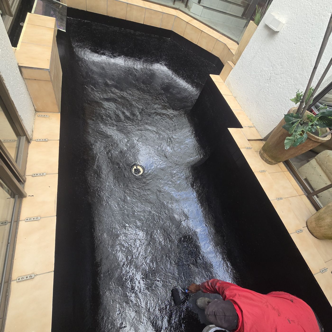 New black sealing coating being rolled onto a pond