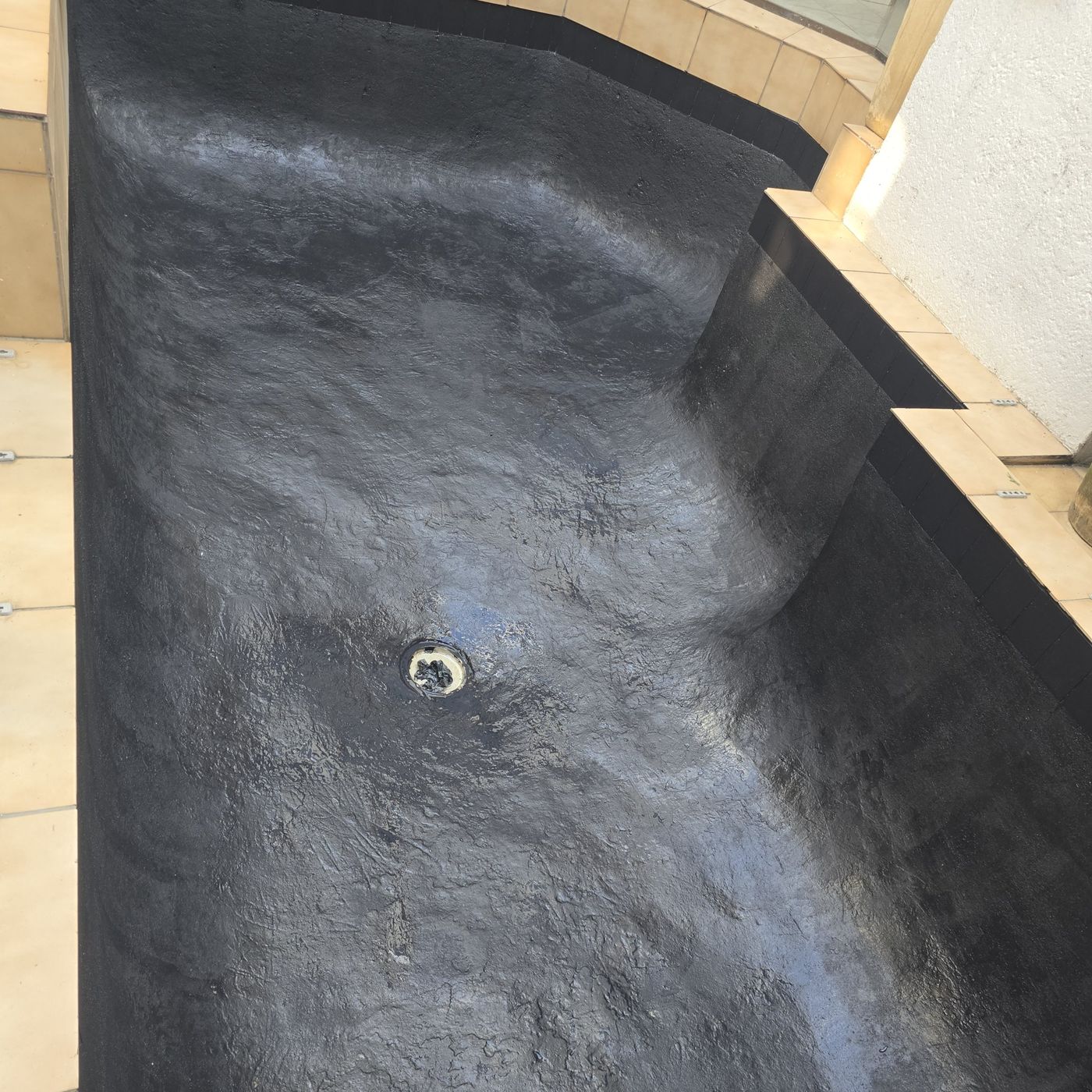 Pond with a finished black sealing coat around the drain