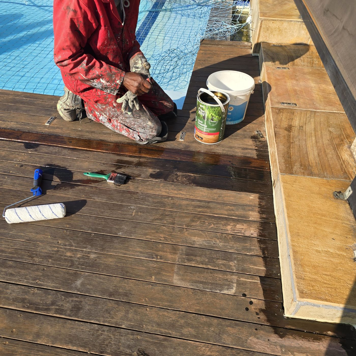 Painter applying deck dressing to a sanded timber pool deck