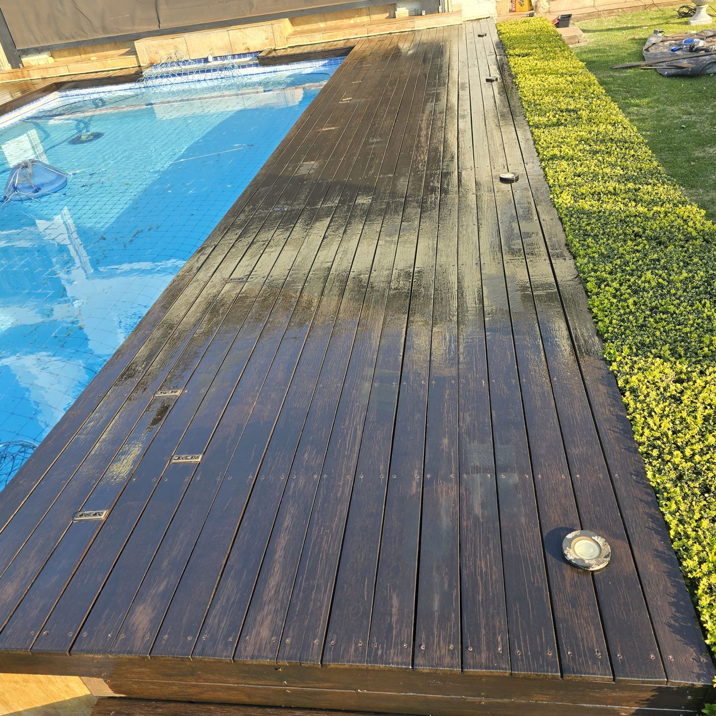 Finished dark timber deck beside a swimming pool